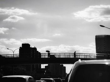 Cars on bridge against sky in city