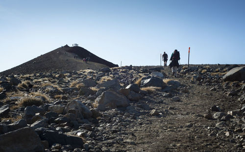 People on rocks against clear sky