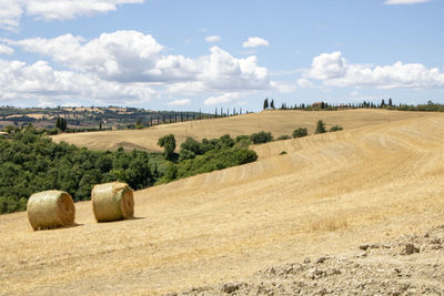 Hay bales on field against sky