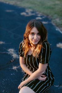 Fashionable teenage girl sitting outdoors