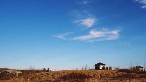 House on landscape against blue sky