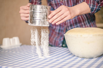 Midsection of woman holding ice cream in bowl on table