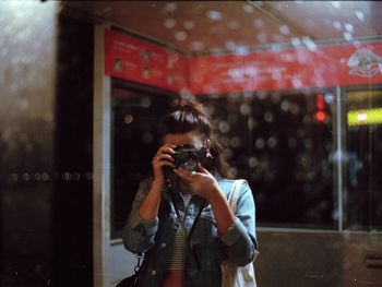 Woman photographing with umbrella standing in rain