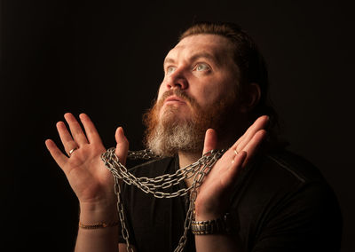 Portrait of man looking away against black background