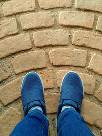 Low section of man standing against brick wall