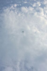 Low angle view of airplane flying in cloudy sky