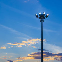 Low angle view of illuminated floodlight against sky during sunset