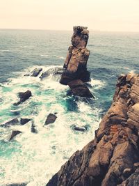 Rock formation on sea shore against sky