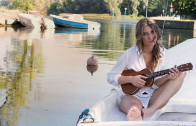 Portrait of young woman holding guitar in boat