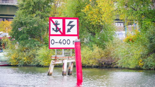 Information sign by lake against trees