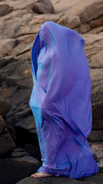 Woman wrapped in curtain while standing on rock