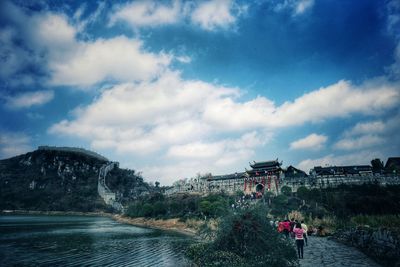 People on mountain against cloudy sky