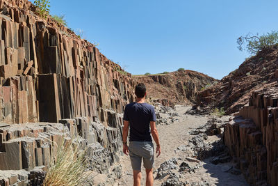 Rear view of man walking on land against sky