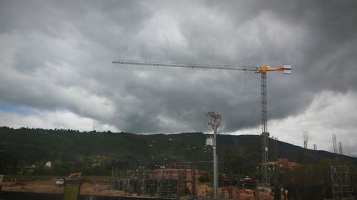 Low angle view of crane against cloudy sky