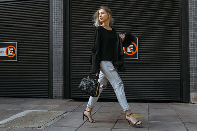 Full length of woman standing against shutter