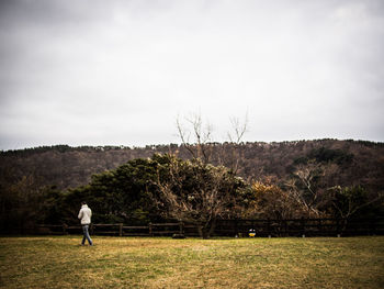 Man playing with ball on grass against sky