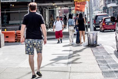 Rear view of people walking on street in city