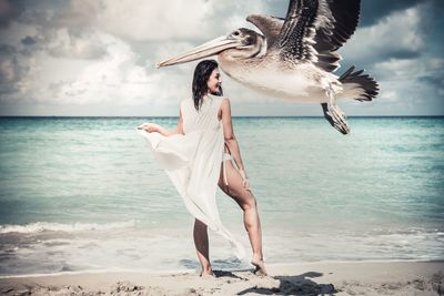 Full length of young woman sitting on beach