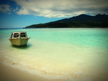 Boat moored on sea shore against sky