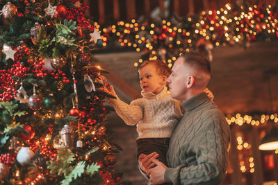 Smile little boy and dad having fun with each other hugs and kisses indoor waiting santa.