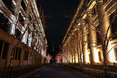 Illuminated street amidst buildings at night