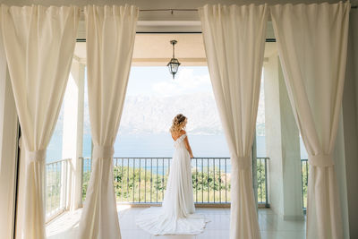 Woman standing against white curtain