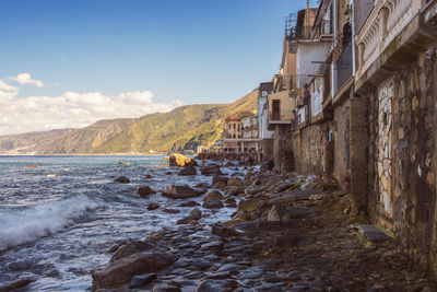 Scenic view of sea by buildings against sky