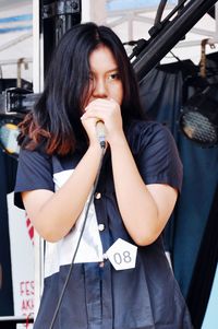 Young woman looking away while holding microphone