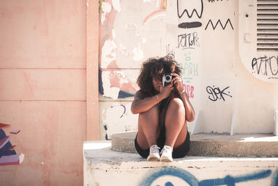 Full length of woman sitting on wall