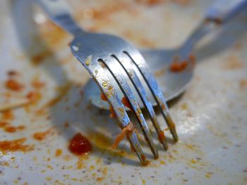 Close-up of spoon and fork with leftovers on plate