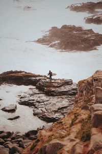 Rear view of man on rock at beach