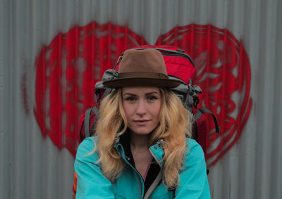 Portrait of young woman against red wall