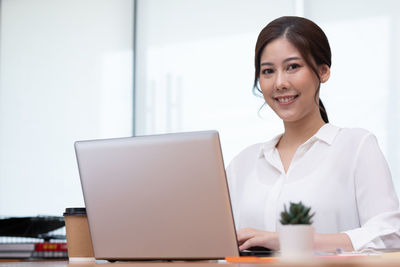 Portrait of young businesswoman using laptop at office