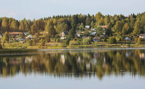 Scenic view of lake by trees and buildings against sky