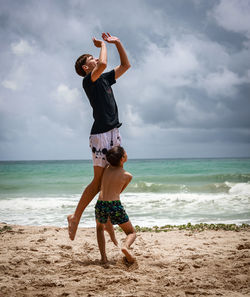 Full length of young woman standing at beach against sky