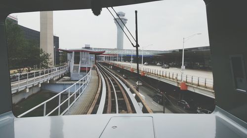 Railway bridge by city street against tower seen through train windshield