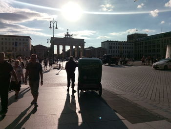 People on sidewalk in city against sky