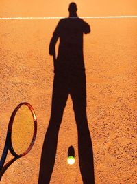 Shadow of tennis player falling on field