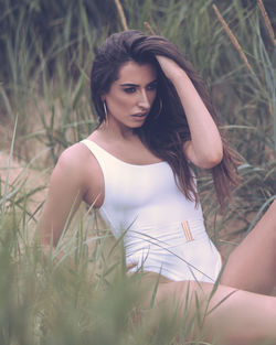 Beautiful young woman posing while sitting on field