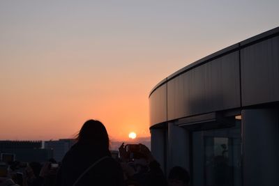 Silhouette of people against clear sky at sunset