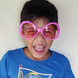 Portrait of screaming boy wearing sunglasses against wall