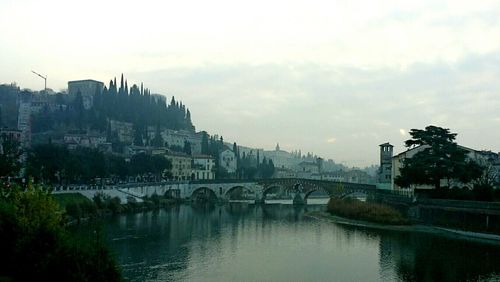 Arch bridge over river against sky in city