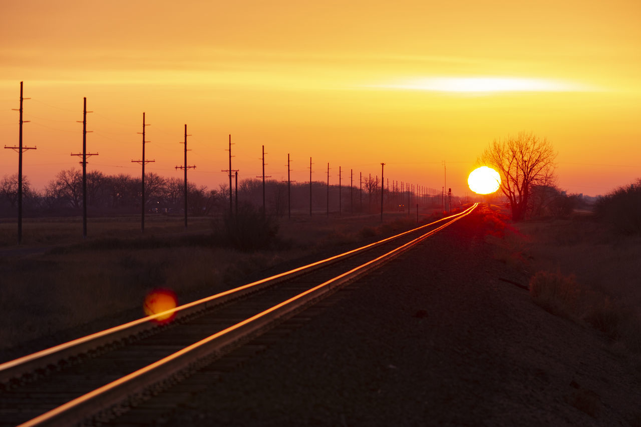 RAILROAD TRACKS AGAINST ORANGE SKY