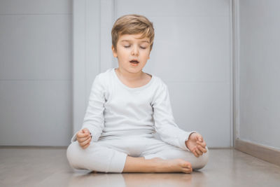 Boy practicing yoga on floor at home