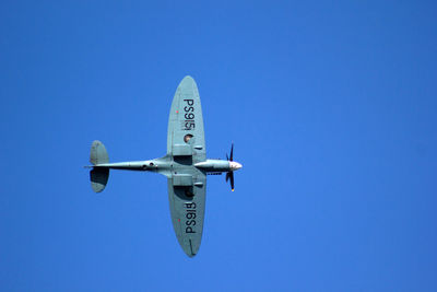 Low angle view of fighter airplane flying against blue sky