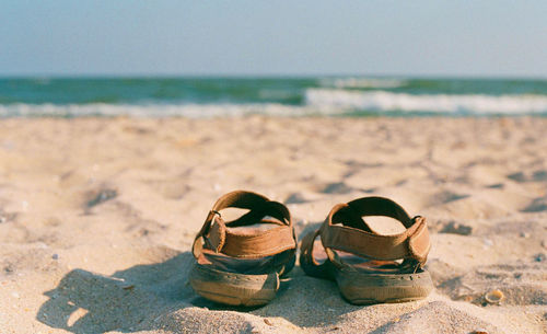 High angle view of shoes on sand at beach against sky