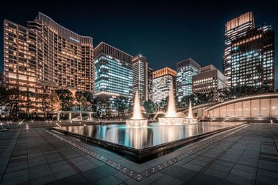 Blurred motion against illuminated modern buildings in city at night