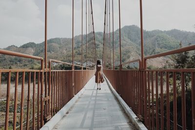 Rear view of man standing on footbridge