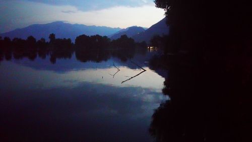 Silhouette trees by lake against sky during sunset