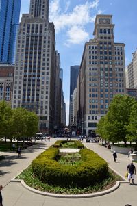 Skyscrapers in park against sky in city